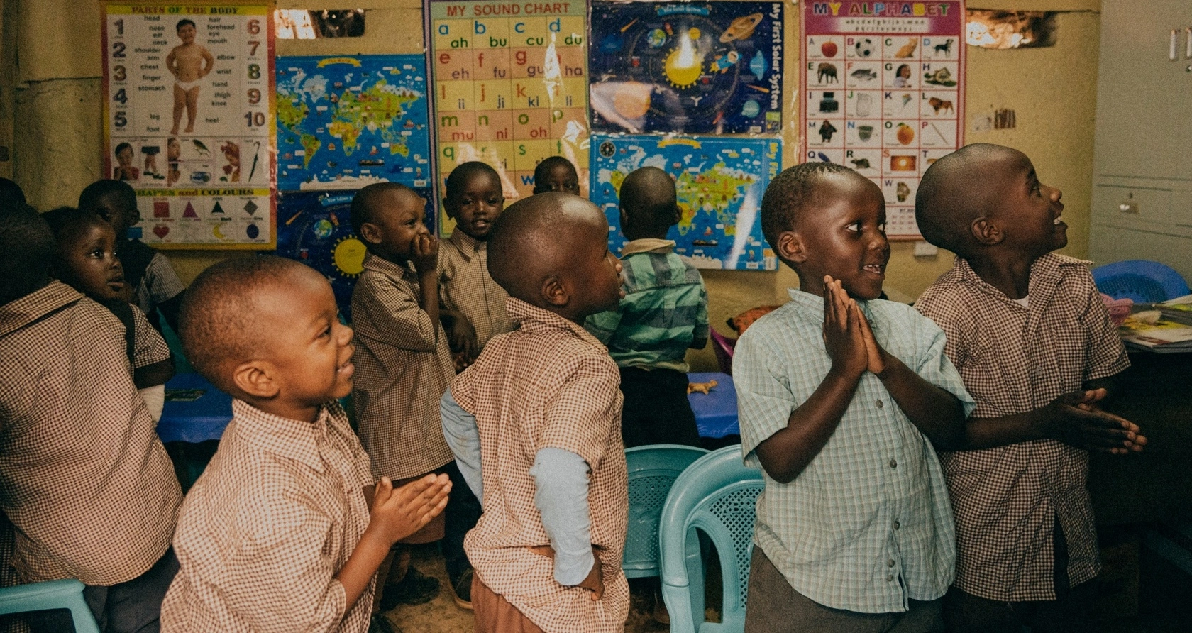 Children are playing inside a classroom of Tabor School. They have educational posters about the human structure, the alphabet, the solar system, and others.