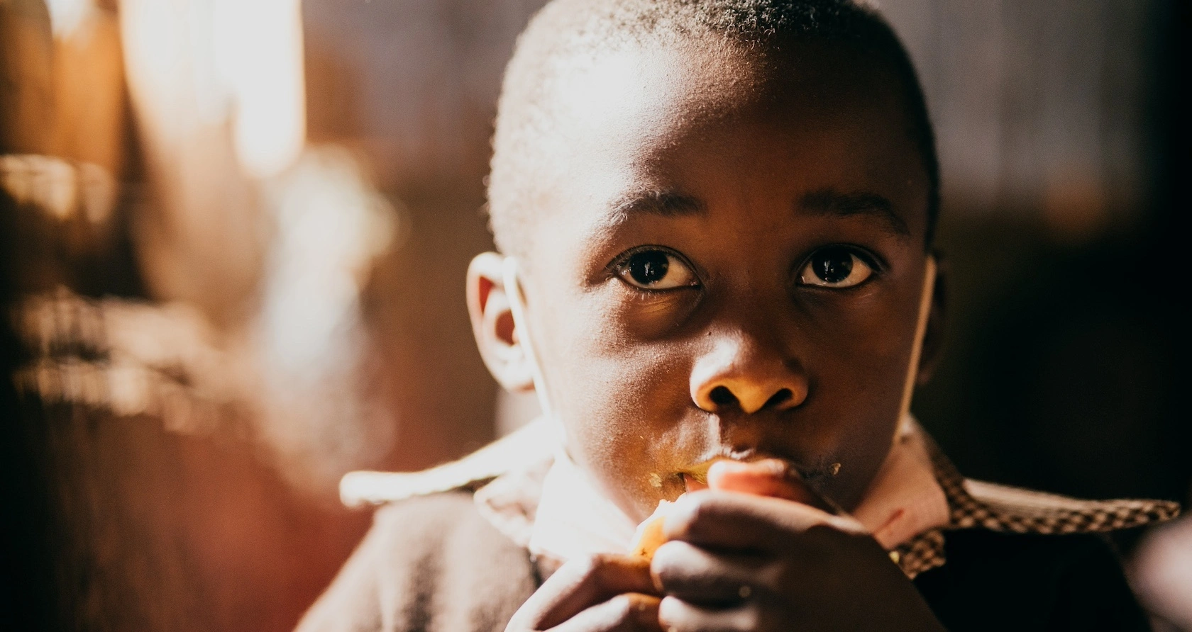 A close up shot of the eyes of a child who eats an orange for an afternoon snack at school